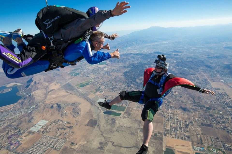Two skydivers jump in the air.