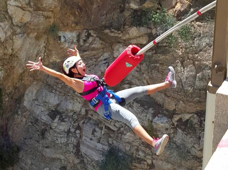 A girl bungee jumps off a bridge backwards.