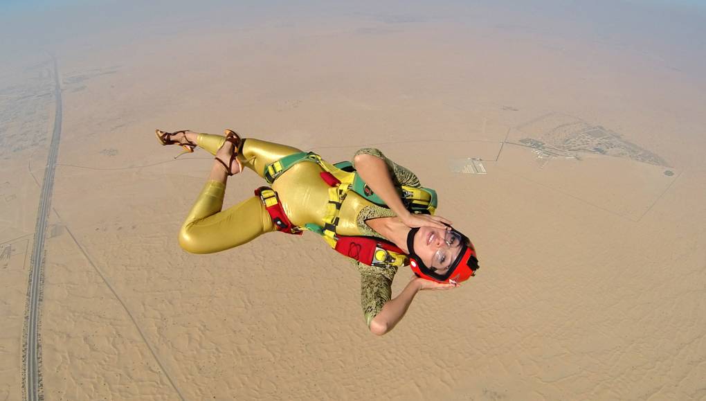 Roberta Mancino posing in free fall while wearing a golden jumpsuit.