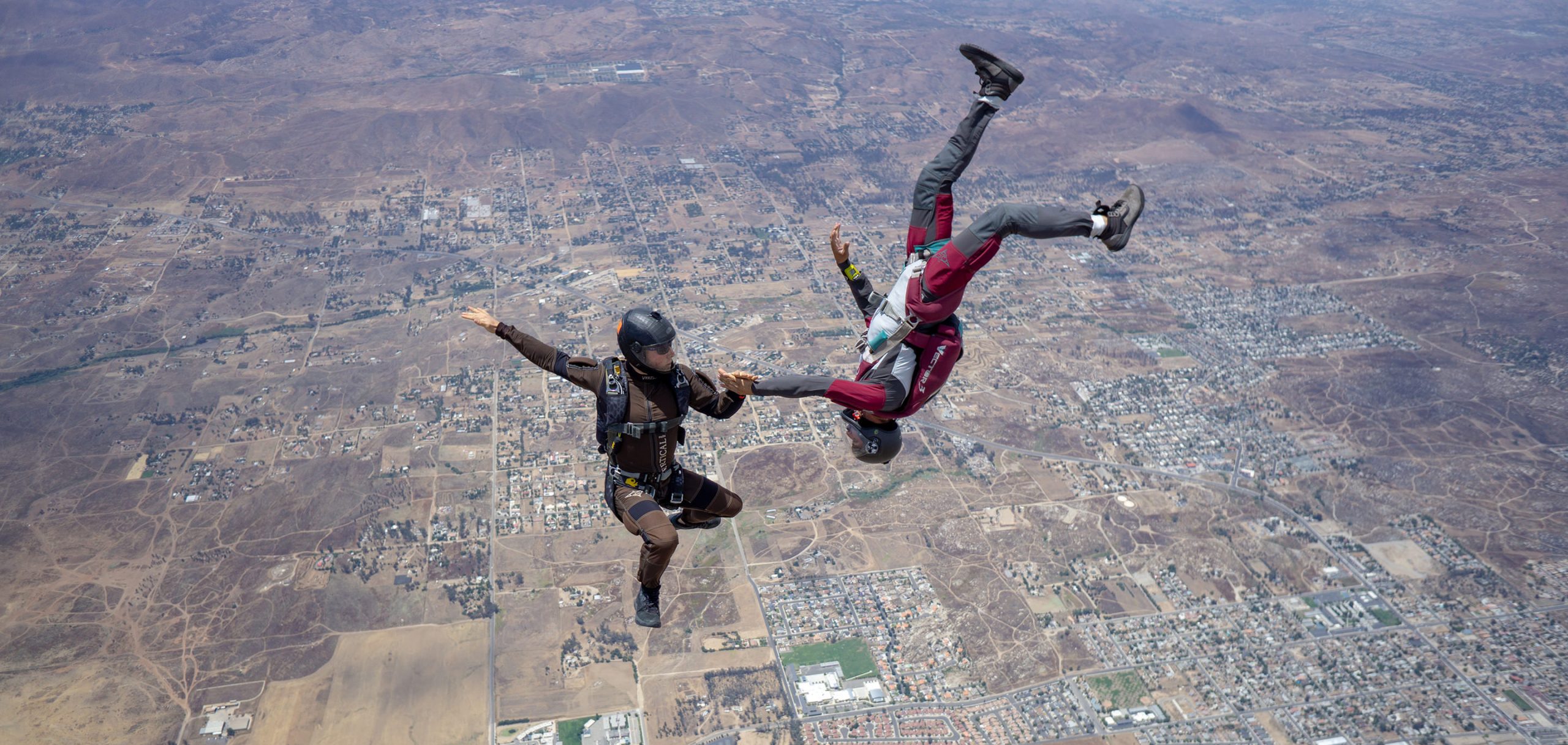 Two skydivers fly through the sky.